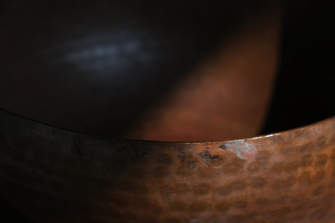 A brass singing bowl without traditional coating, leaving the metal piece with naked surface, natural burn marks and unique reddish due to burning reaction.