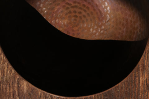 A brass singing bowl without traditional coating, leaving the metal piece with naked surface, natural burn marks and unique reddish due to burning reaction.