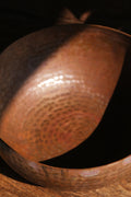 A brass singing bowl without traditional coating, leaving the metal piece with naked surface, natural burn marks and unique reddish due to burning reaction.