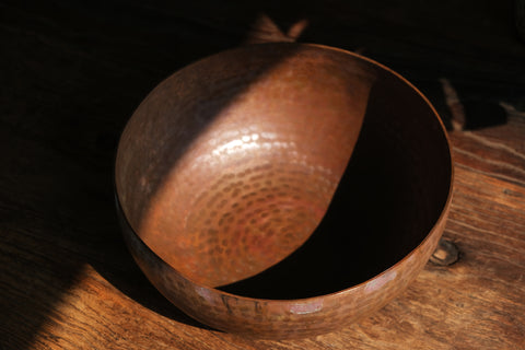 A brass singing bowl without traditional coating, leaving the metal piece with naked surface, natural burn marks and unique reddish due to burning reaction.