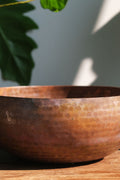 A brass singing bowl without traditional coating, leaving the metal piece with naked surface, natural burn marks and unique reddish due to burning reaction.