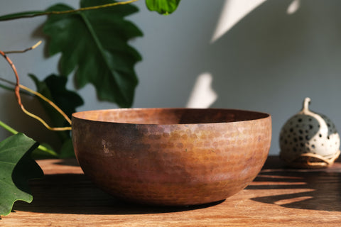 A brass singing bowl without traditional coating, leaving the metal piece with naked surface, natural burn marks and unique reddish due to burning reaction.